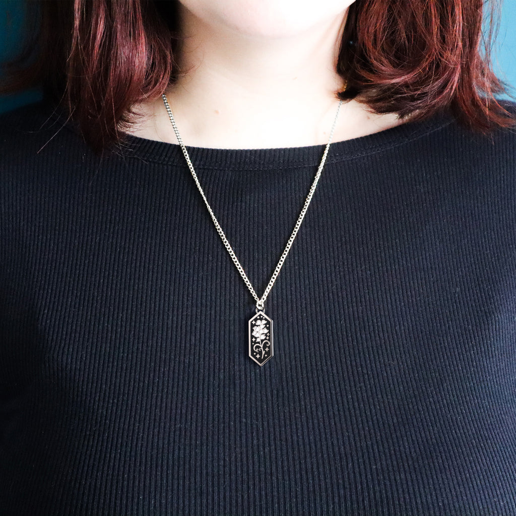 A silver bluebells necklace being worn by a model wearing a black top.