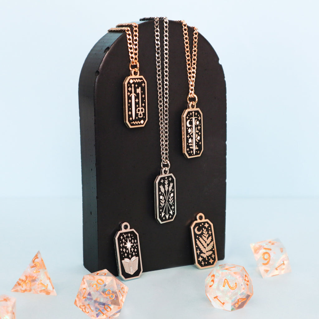 A group photograph of a selection of necklaces. The necklaces are draped over a black concrete slab on a blue background.