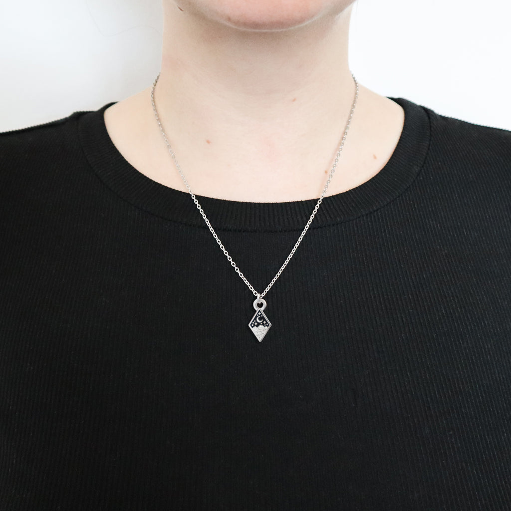 A silver mountains necklace being worn by a model wearing a black top.