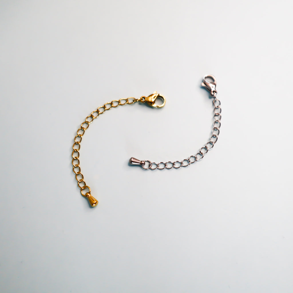 Two necklace extender, one silver and one gold on a light blue background. 